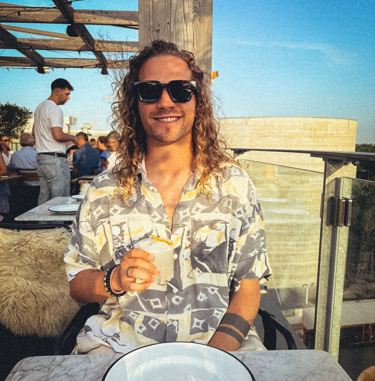 Sandro, founder of Canvas Comrade, smiling in sunglasses on a sunny terrace