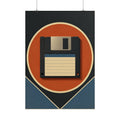 A framed wall art print featuring a retro 1980s floppy disk design hangs above a wooden desk in a styled home office setting with a keyboard, notebook, lamp, and plant.