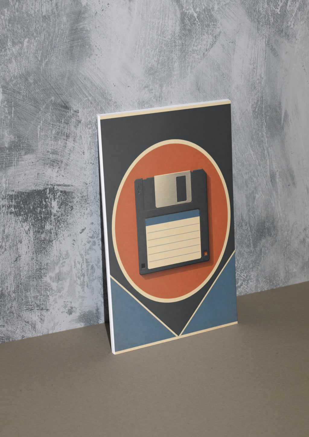 A vertical art print featuring a retro 1980s floppy disk illustration, leaning against a textured gray concrete wall on a neutral beige surface.